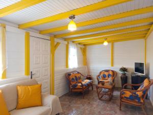 a porch with chairs and a couch and a tv at Maison charmante à Le Diamant avec vue sur mer et jardin in Le Diamant
