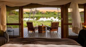 a bedroom with a bed and two chairs on a deck at Onguma Tented Camp in Mokuti Lodge