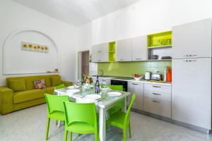 a kitchen with a table and green chairs in a room at Villa Anny Fronte Mare in Avola +28 photos
