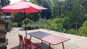 a table and chairs with a red umbrella on a deck at ricochets in Castillon +2 photos