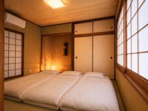 two beds in a room with two windows at オリーブママのヤド 凪 バーベキュー機材レンタル可 in Shodoshima