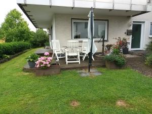 a porch with chairs and an umbrella and flowers at Ferienwohnung am Wald in Warstein