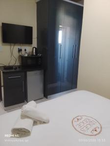 a bedroom with a bed with a cabinet and a television at LINGE'S LODGE EXTENSION in Lusikisiki