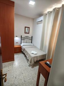 a small bedroom with a bed and a table at H Arkanta in Arganda del Rey
