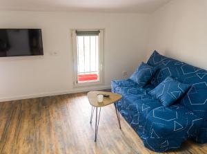 a living room with a blue couch and a table at Studio charmant à Saint-Jory, 25 m², piscine partagée in Saint-Jory