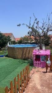 a pink play house in a yard with a pool at Casinha do coração do Oeste in Cadaval