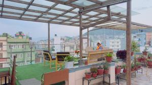 a woman sitting at a table on a balcony with plants at Local feeling in Nepal in Bhaktapur