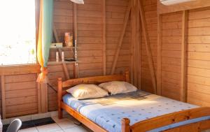 a bedroom with a bed in a room with wooden walls at Bungalow charmant au Gosier in Le Gosier