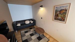 a living room with a black couch and a table at Hotel Péz Regina in Lumbrein