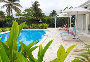 a swimming pool with chairs and an umbrella at Appartement cosy à Sainte Rose / 50 m² / Piscine partagée in Diavet