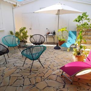 a patio with chairs and tables and an umbrella at Appartement cosy à Sainte Rose / 50 m² / Piscine partagée in Diavet