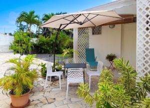 a patio with a table and chairs and an umbrella at Appartement cosy à Sainte Rose / 50 m² / Piscine partagée in Diavet +15 photos