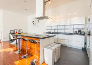 a kitchen with white cabinets and a counter with stools at Spacious House with Large Garden in Jette in Brussels