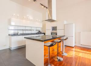 a kitchen with white cabinets and a counter with stools at Spacious House with Large Garden in Jette in Brussels