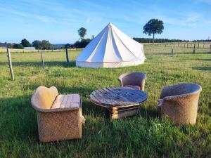 three chairs and a table and a tent in a field at Le Nid des Prairies in La Chapelle-Engerbold +5 photos