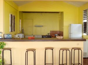 a kitchen with yellow walls and stools at a counter at Maison spacieuse avec piscine privée à Le François in Le François