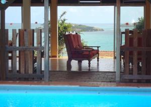 a chair sitting on a porch with a view of the ocean at Maison spacieuse avec piscine privée à Le François in Le François