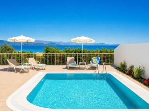 a pool with chairs and umbrellas on a patio at Villa Alora in Barbati
