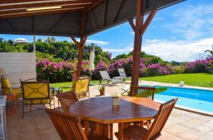 a patio with a wooden table and chairs and a pool at Villa cosy avec piscine privée - Le Gosier. in Le Gosier