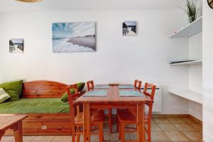 a dining room with a table and chairs and a couch at Appartement chez Coco avec piscine in Soulac-sur-Mer +18 photos