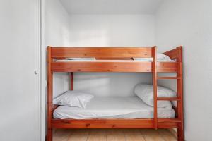 a wooden bunk bed with white sheets and pillows at Appartement chez Coco avec piscine in Soulac-sur-Mer