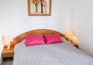 a bedroom with a bed with two pink pillows at Maison charmante à San-Nicolao avec piscine partagée in San-Nicolao