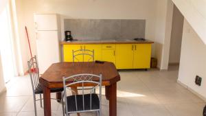 a kitchen with a wooden table and yellow cabinets at Appartement confortable à Capesterre, 40 m², jardin agréable in Rabi