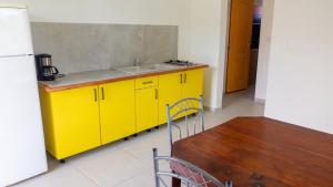 a yellow kitchen with a sink and a table at Appartement confortable à Capesterre, 40 m², jardin agréable in Rabi