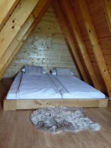 a bed in a wooden attic with a rug at Glamping Čelig in Donja Višnjica