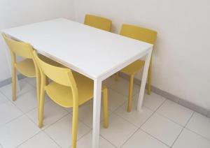 a white table with four yellow chairs around it at Campeggio 2 Mari in Ovile la Marinella