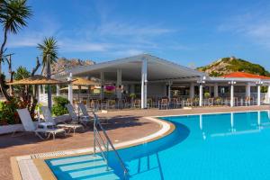 a pool with chairs and umbrellas next to a resort at Leonardo Kolymbia Resort Rhodes in Kolymbia