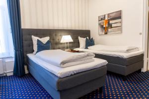 zwei Betten in einem Hotelzimmer mit einer Lampe in der Unterkunft Hotel Phønix Aalborg in Aalborg + 12 Fotos