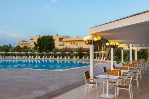 a row of tables and chairs next to a pool at Leonardo Kolymbia Resort Rhodes in Kolymbia +23 photos