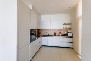 a white kitchen with white cabinets and appliances at Vila IL SOLE GREEN COAST in Palasë
