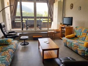 a living room with couches and a tv and a table at Studio avec vue sur la montagne à Villard de Lans - 34 m² in Villard-de-Lans