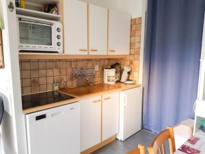 a small kitchen with white cabinets and a microwave at Studio avec vue sur la montagne à Villard de Lans - 34 m² in Villard-de-Lans +21 photos