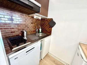 a small kitchen with a sink and a brick wall at Reflet d’Azur - 4 personnes - Point zéro in La Grande Motte
