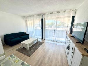 a living room with a blue couch and a tv at Reflet d’Azur - 4 personnes - Point zéro in La Grande Motte +5 photos