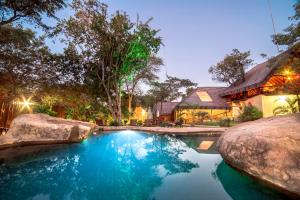 a house with a swimming pool in front of a house at Pezulu Tree House Lodge in Hoedspruit