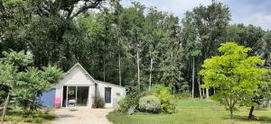 a small white house in the middle of a yard at Le bois des Mottouses in Pellouailles-les-Vignes