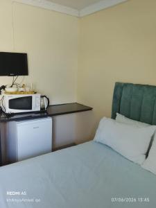 a hotel room with a bed and a microwave at LINGE'S LODGE EXTENSION in Lusikisiki