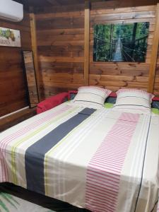 a large bed in a room with wooden walls at Maison cosy avec piscine partagée à Capesterre-Belle-Eau in Besnard