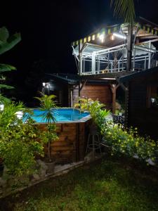 a hot tub in the backyard of a house at night at Maison cosy avec piscine partagée à Capesterre-Belle-Eau in Besnard