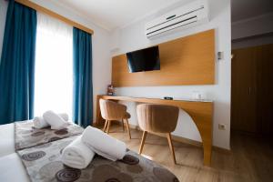 Una habitación de hotel con una cama, un escritorio y un televisor. en Olympion, en Atenas