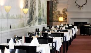 a dining room with white tables and black chairs at Kurzentrum Ludwigstorff GmbH in Deutsch Altenburg