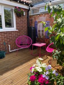 two pink chairs and tables on a patio with flowers at Double Bedroom with Private Entrance in Weymouth +11 photos