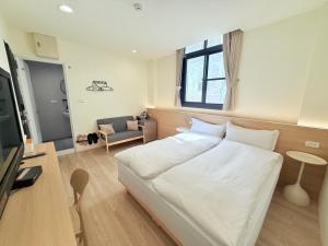 a bedroom with a large white bed in a room at Jian Guo Hotel in Pingtung City