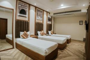 a hotel room with two beds and a tv at Hotel Asopalav in Junagadh