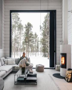 a man sitting on a couch in a living room with a fireplace at Polaris Villas - Villa Deluxe in Muonio