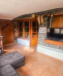 a living room with a tv on a stone wall at Spacious House in Canejan with Mountain View in Caneján